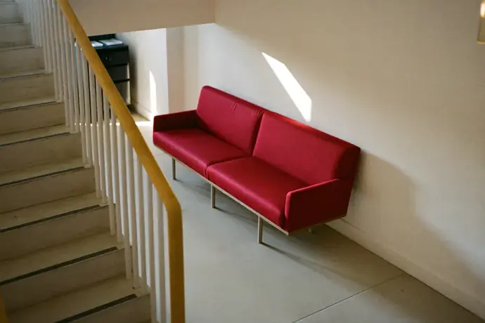 Empty stairwell landing in a corporate office with a single crimson bench