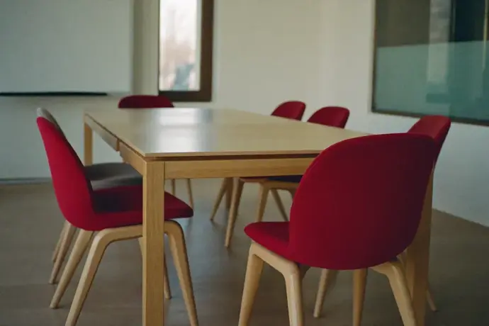 Empty boardroom set for a decision meeting, one crimson chair at the head of the table