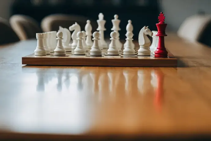 A chessboard with rows of white pieces and a single crimson king standing apart
